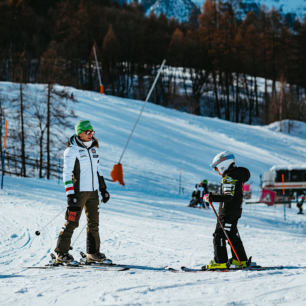 un momento delle lezioni di sci di Liberi Tutti: una maestra con un giovane allievo